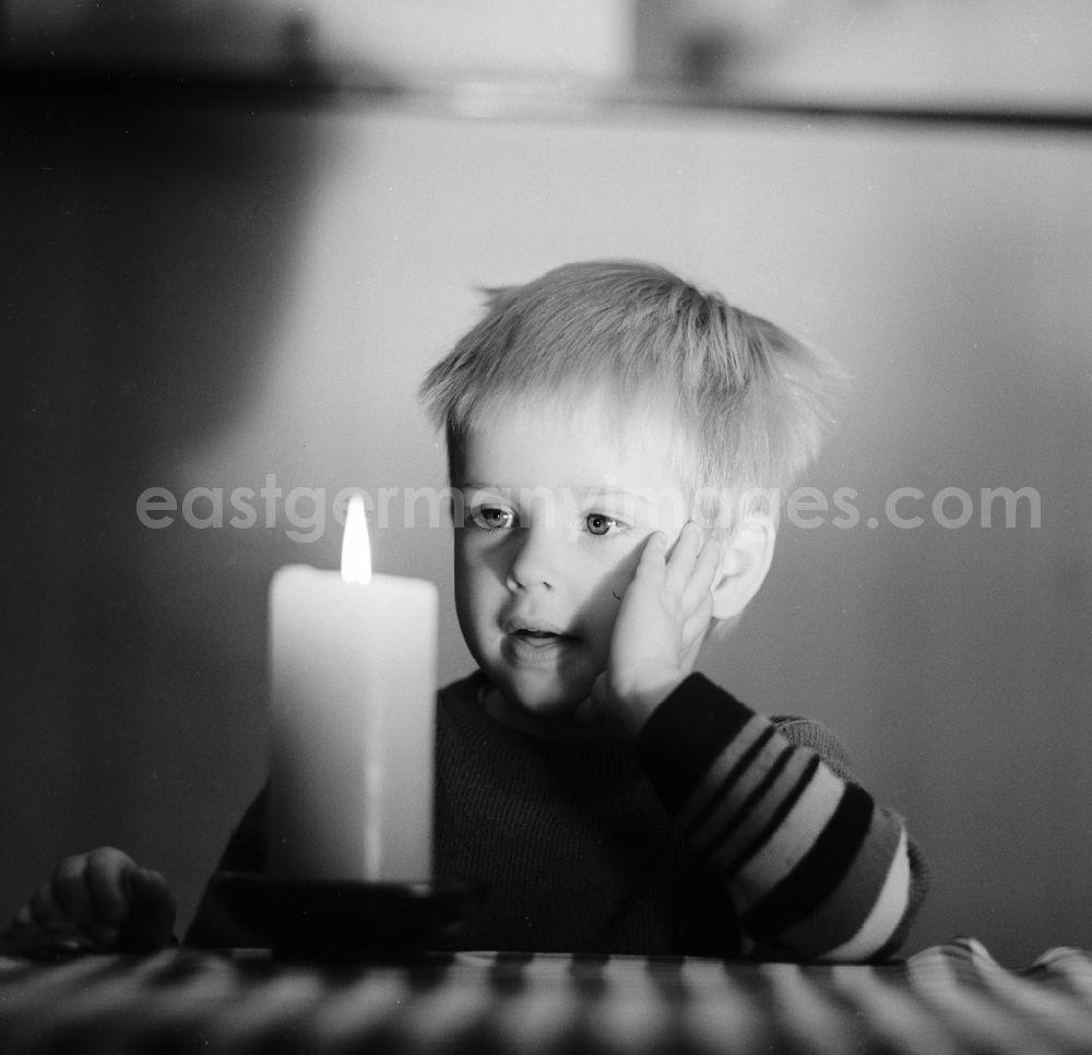 GDR image archive: Berlin - A small child marvels at a burning candle standing on a table in Berlin, the former capital of the GDR, German Democratic Republic