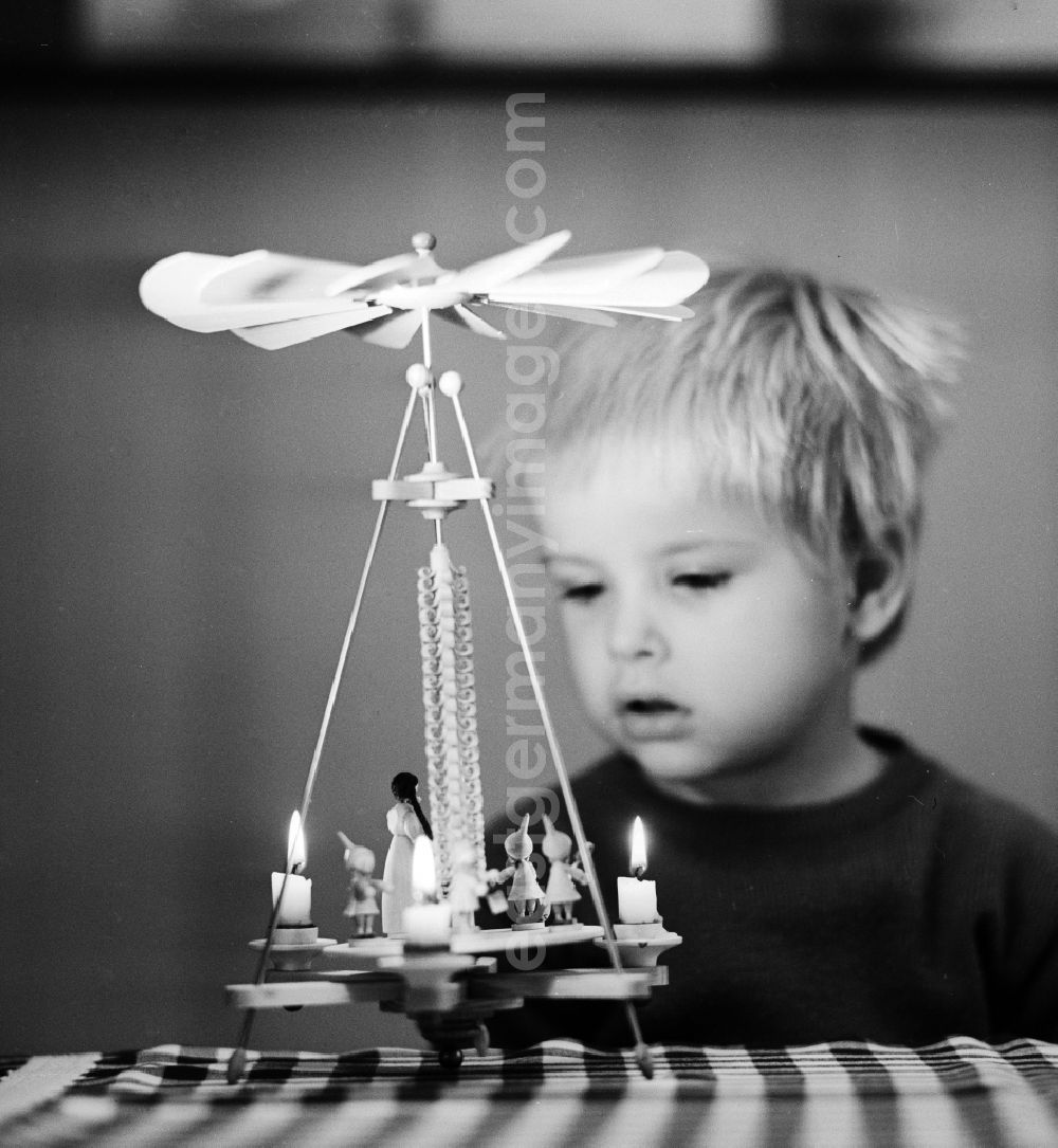 GDR picture archive: Berlin - A small child marvels at a Christmas pyramid made of wood in Berlin, the former capital of the GDR, German Democratic Republic