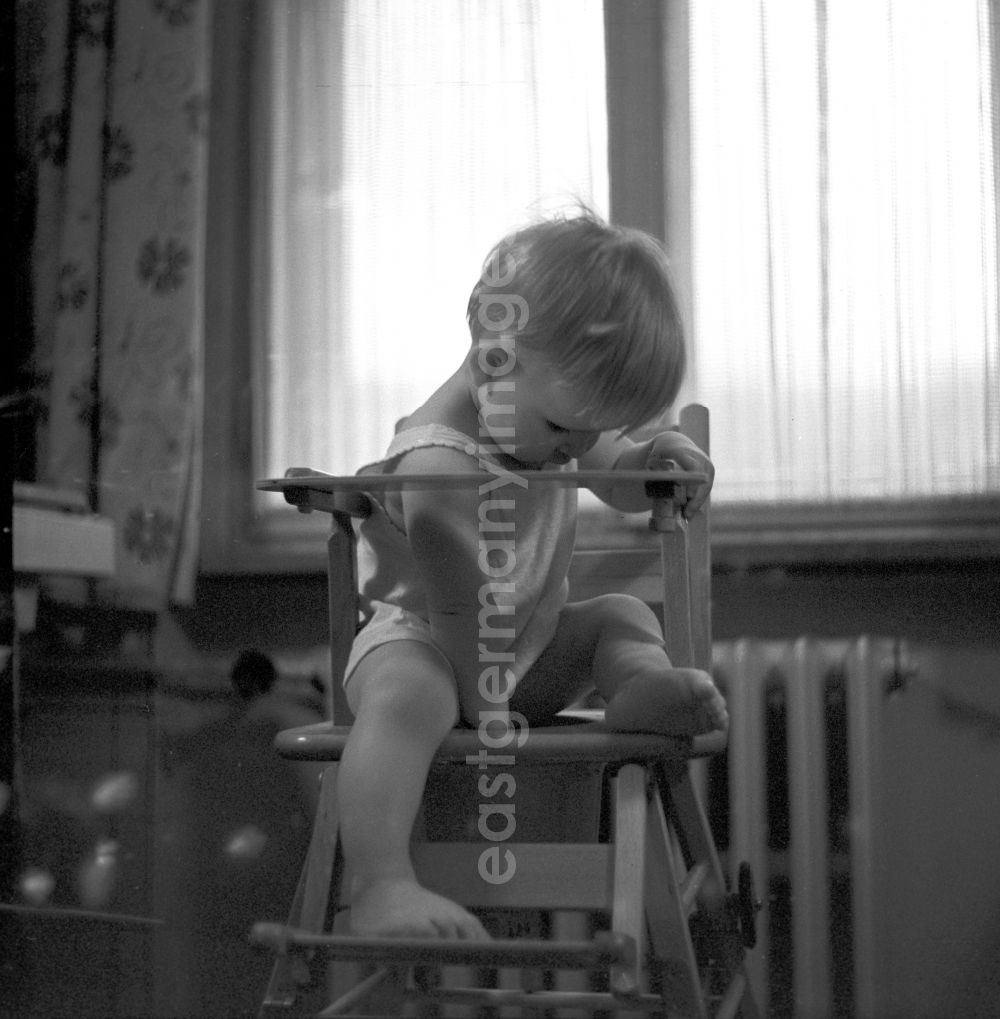 GDR picture archive: Berlin - Friedrichshain - Ein kleines Kind in einem Hochstuhl aus Holz in Berlin - Friedrichshain.// A small child in a high chair made ??of wood in Berlin - Friedrichshain.