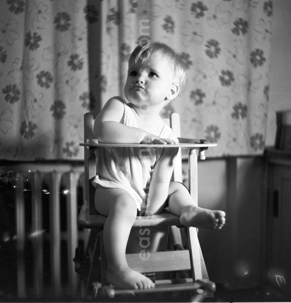 GDR image archive: Berlin - Friedrichshain - Ein kleines Kind in einem Hochstuhl aus Holz in Berlin - Friedrichshain.// A small child in a high chair made ??of wood in Berlin - Friedrichshain.