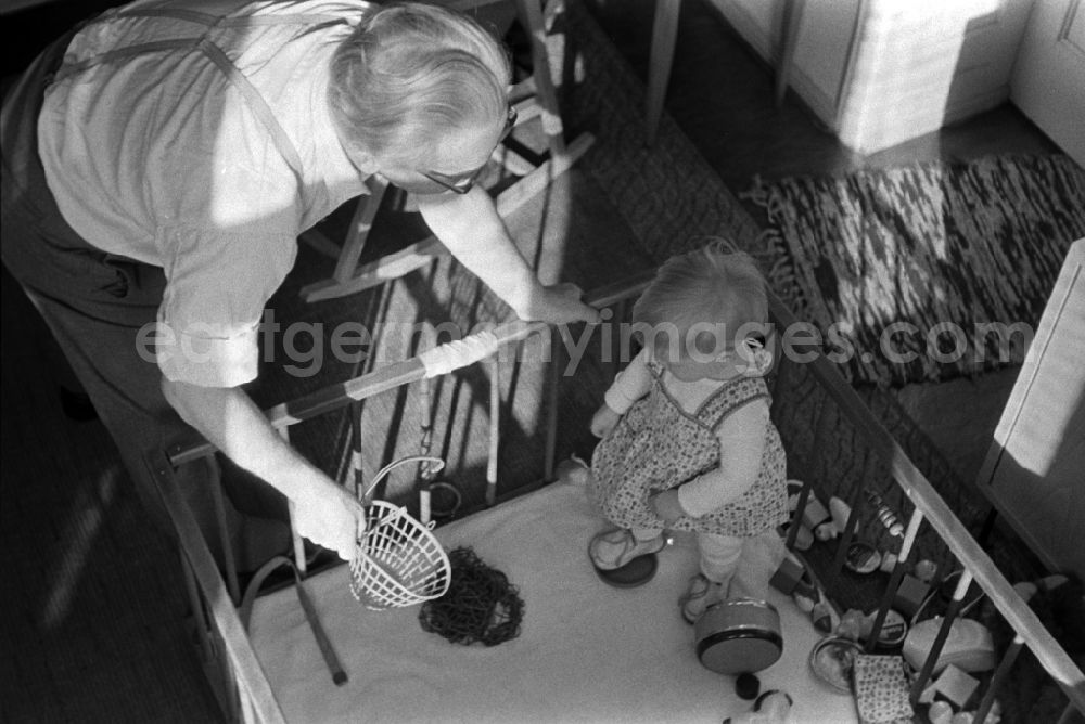 GDR photo archive: Berlin - Friedrichshain - A small child with toy in playpen in Berlin - Friedrichshain