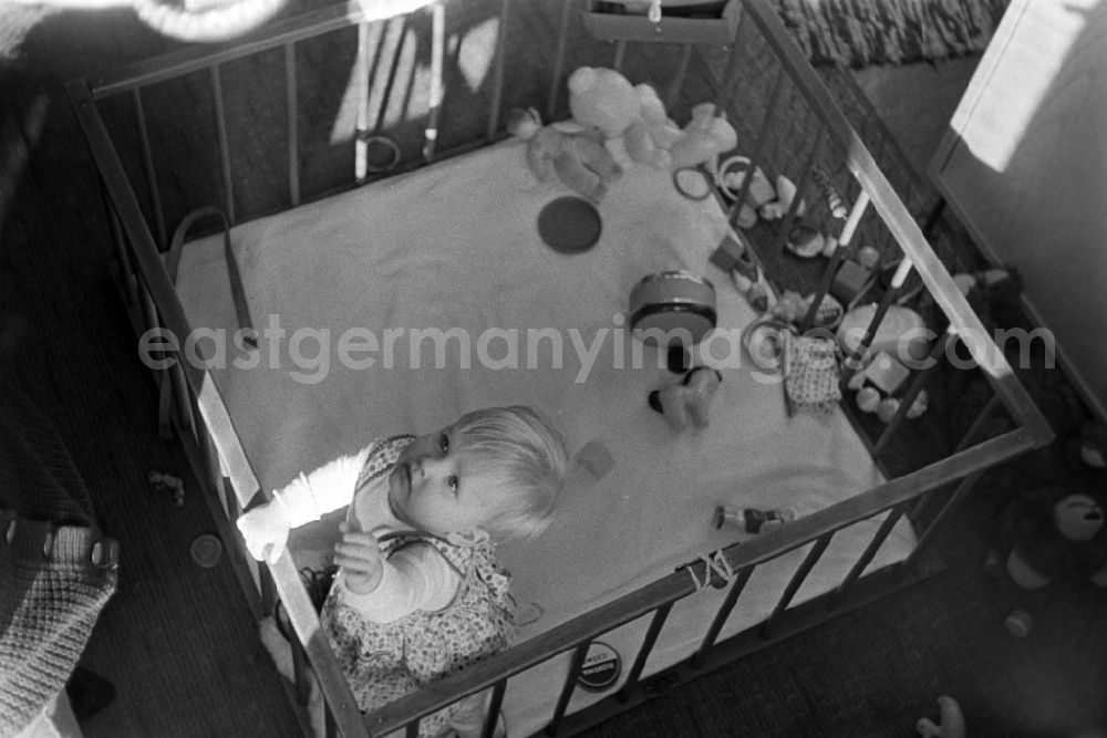 GDR picture archive: Berlin - Friedrichshain - A small child with toy in playpen in Berlin - Friedrichshain