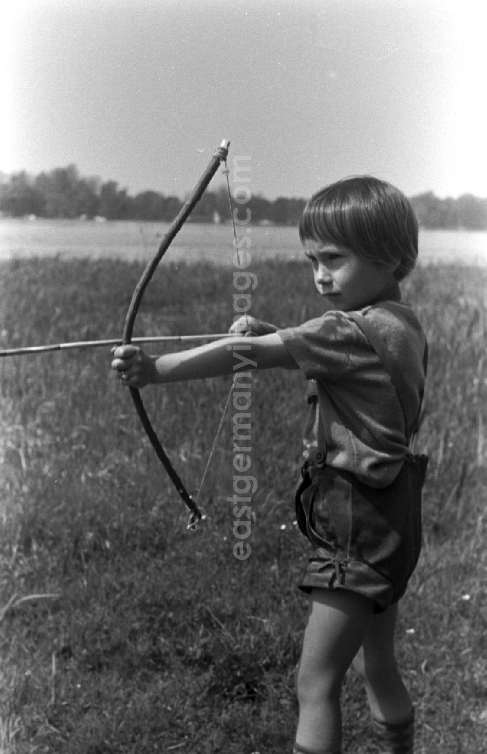 GDR image archive: Kirchmöser - A small child in leather pants playing with bow and arrow on a meadow in Brandenburg