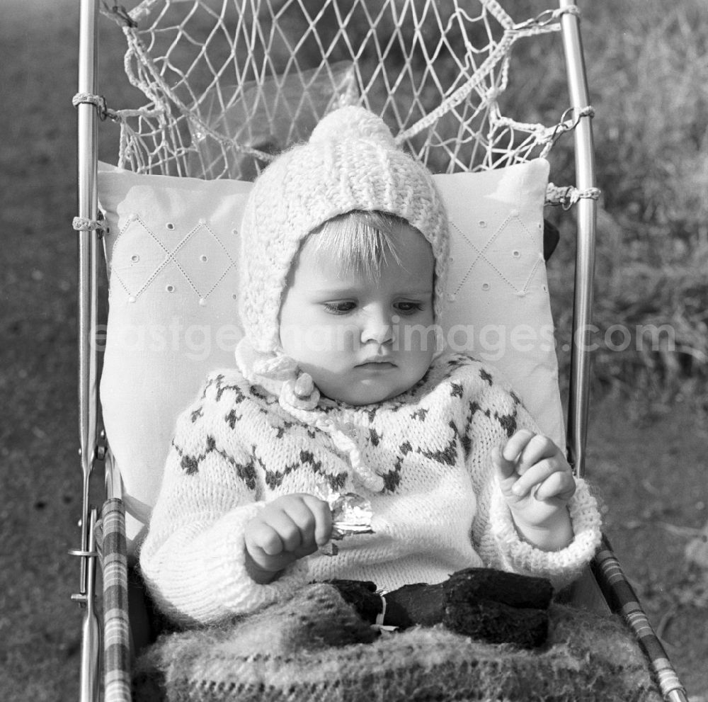GDR picture archive: Magdeburg - Small child with bobble hat sitting in a pram in Magdeburg