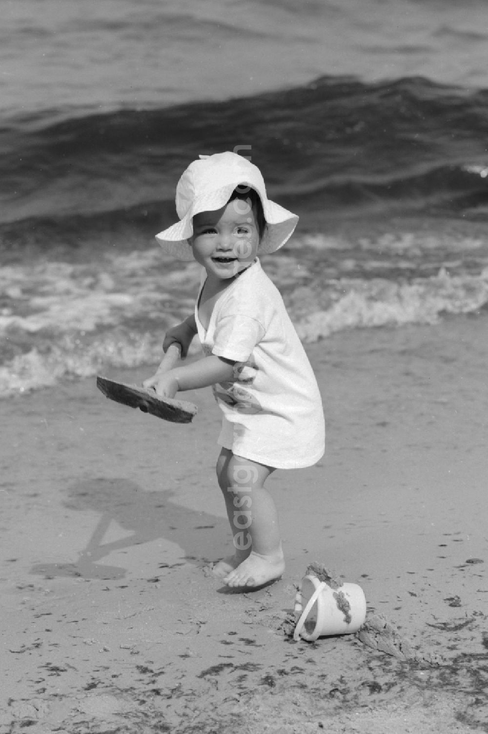 GDR photo archive: Ückeritz - Little child with shovel and pail on the beach in Ueckeritz in Mecklenburg-Western Pomerania in the field of the former GDR, German Democratic Republic