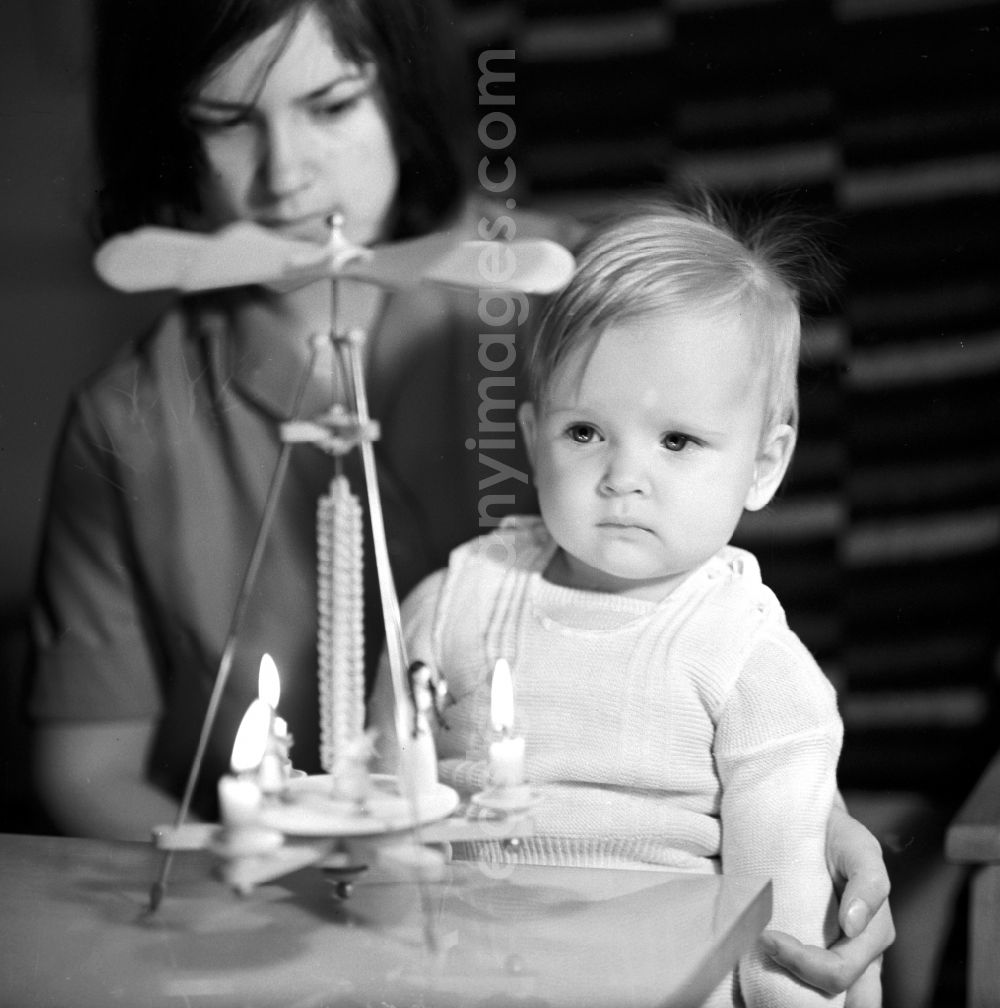 GDR picture archive: Berlin - Friedrichshain - A small child sitting on his mother's lap in front of a pyramid with candles in Berlin - Friedrichshain