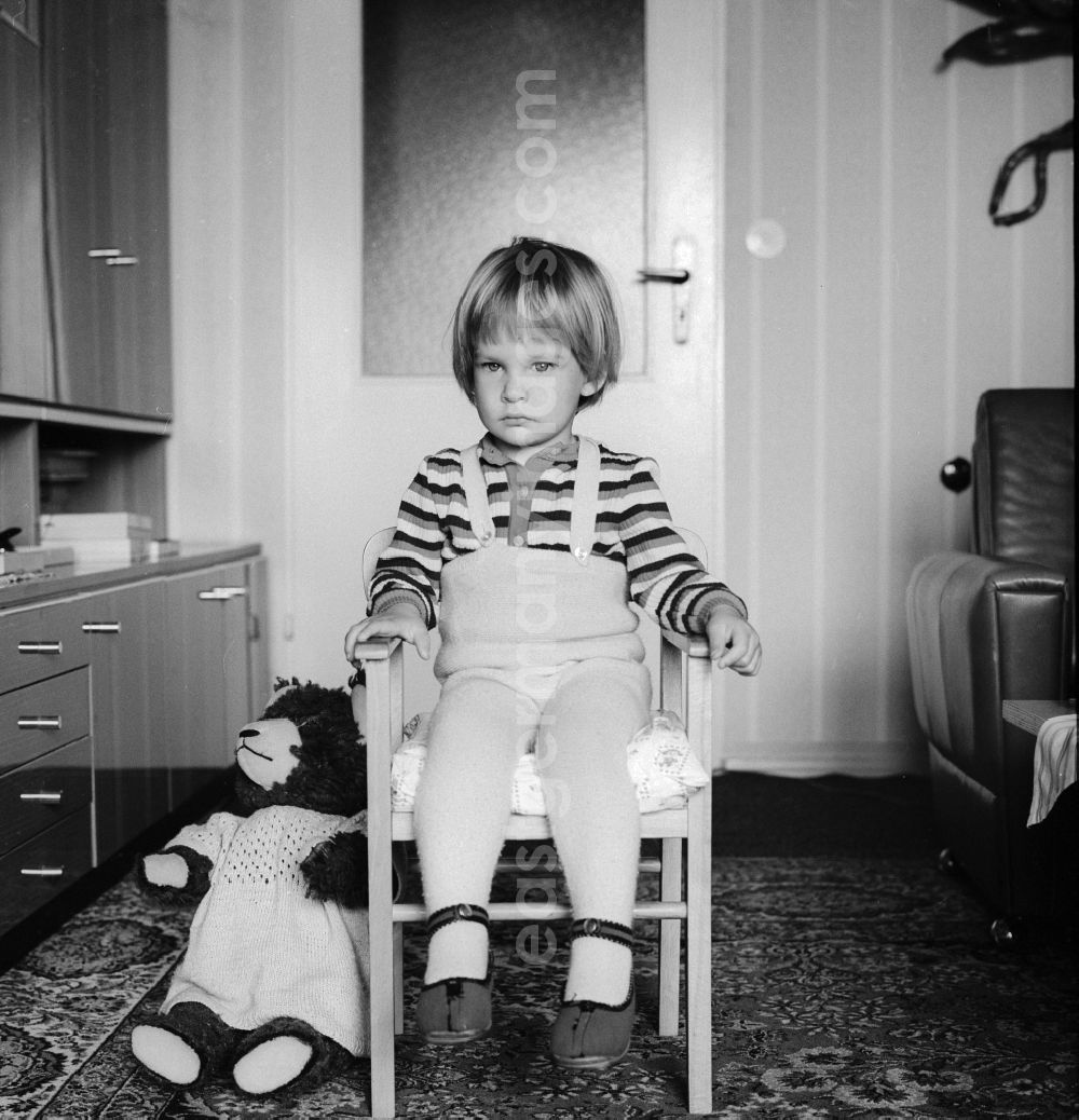 GDR photo archive: Berlin - Cute little baby sitting dreamily on a chair in Berlin