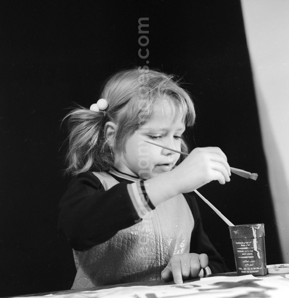 GDR picture archive: Berlin - A little girl with pigtails painting with brush and ink in Berlin, the former capital of the GDR, German Democratic Republic