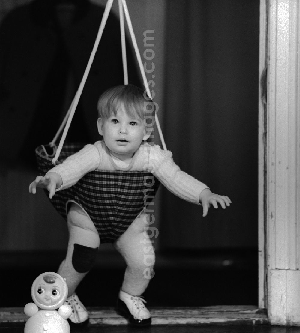 GDR image archive: Berlin - Toddler in a baby swing mounted in a door frame in Berlin