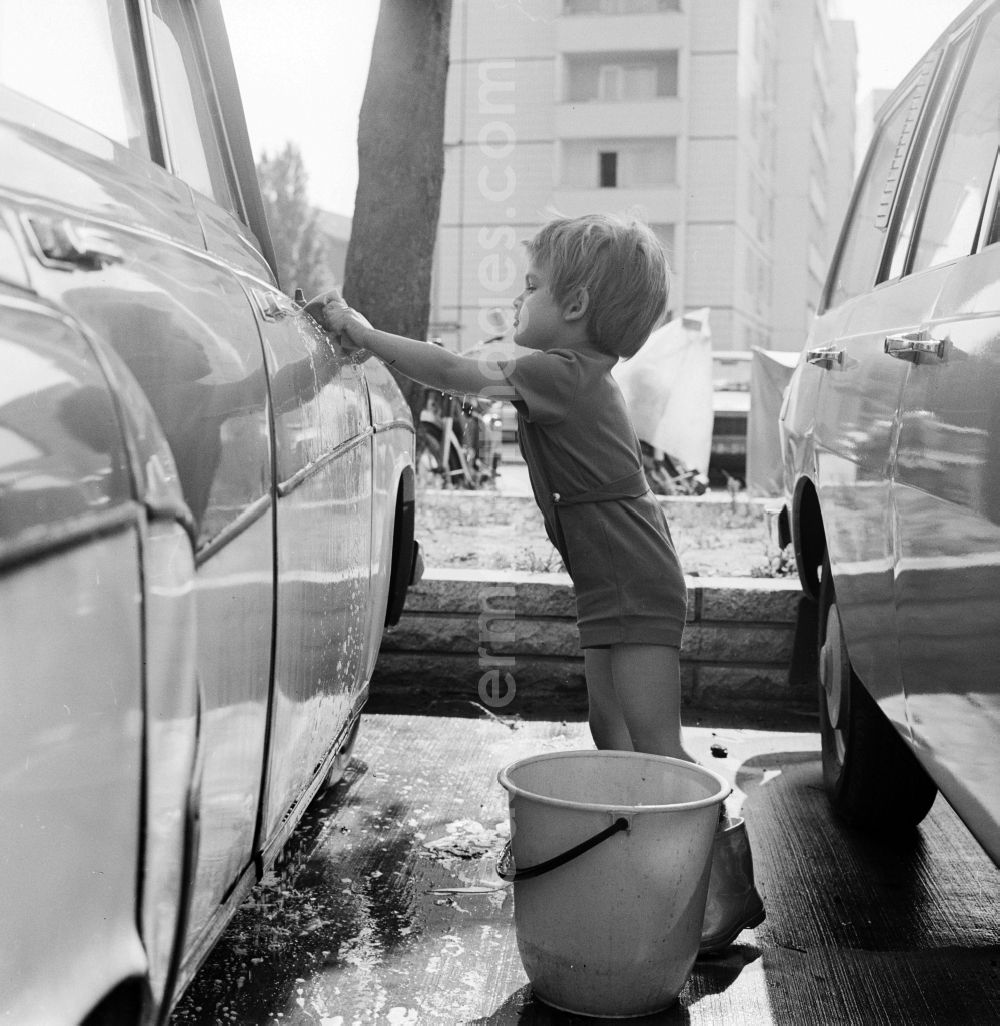GDR image archive: Berlin - A toddler with rubber boots and bucket at the car wash in a parking lot in Berlin, the former capital of the GDR, the German Democratic Republic