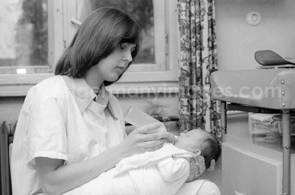 GDR photo archive: Berlin - A nurse of the clinic for paediatrics and youth medicine lime court gives to a baby the teat bottle in Berlin, the former capital of the GDR, German democratic republic. The children - hospital Lindenhof are a component of the Sana medical centres in the Berlin district bright mountain