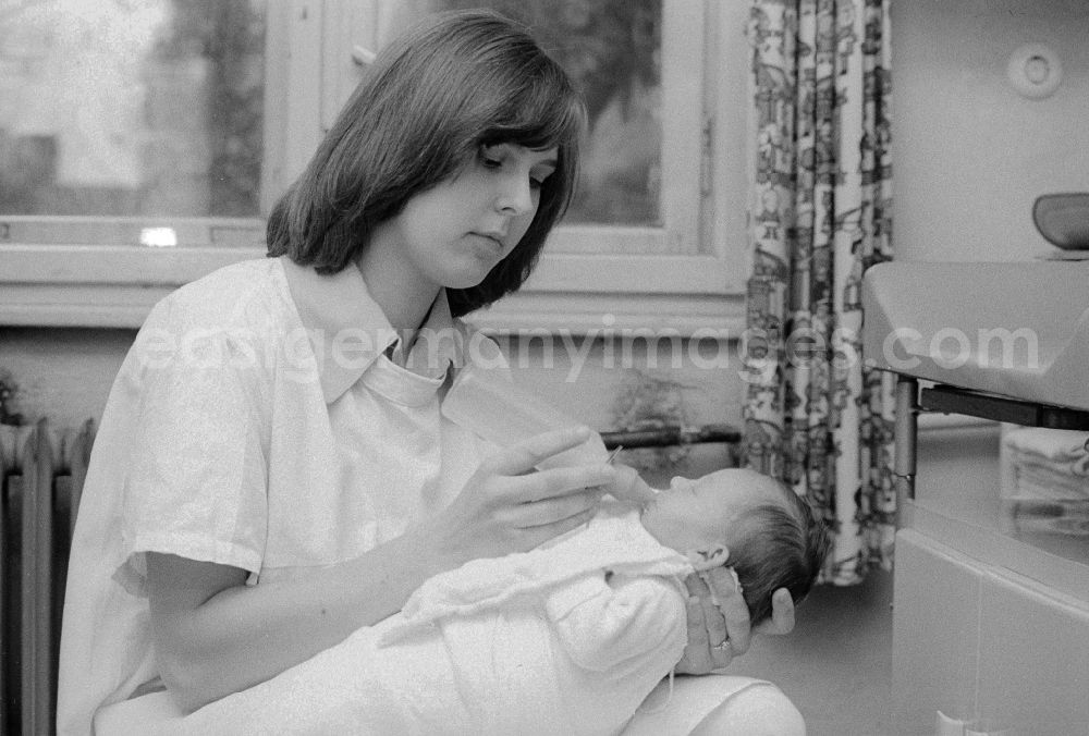 GDR picture archive: Berlin - A nurse of the clinic for paediatrics and youth medicine lime court gives to a baby the teat bottle in Berlin, the former capital of the GDR, German democratic republic. The children - hospital Lindenhof are a component of the Sana medical centres in the Berlin district bright mountain