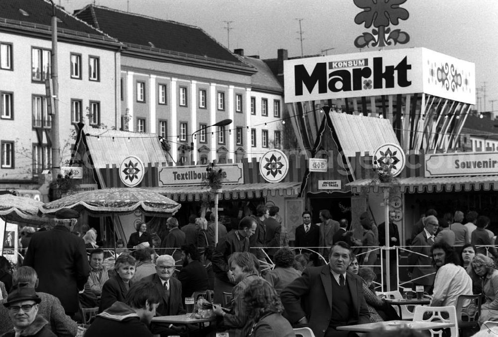 GDR image archive: Merseburg - Blick auf den gut besuchten Konsum Markt in Merseburg. Transparent / Werbebanner mit der Aufschrift Konsum Markt im Hintergrund. Passanten sitzen an Tischen und Buden beim Essen und Trinken.