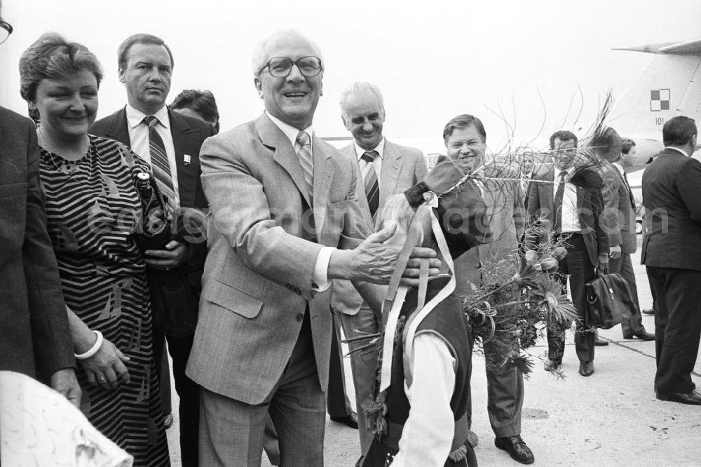 GDR photo archive: Krakau - Staatsbesuch von Erich Honecker, Staatsratsvorsitzender in der Volksrepublik Polen. Honecker bekommt von kleinen Junge / Kind in Volkstracht einen Blumenstrauß überreicht. Beiligte stehen drumherum. Im Hintergrund Passagierflugzeug Tupolew TU-134.