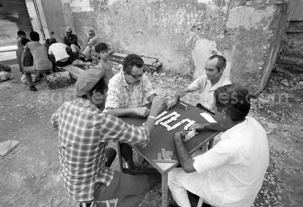 GDR picture archive: Havanna - Männer beim Dominospiel in der Nähe des Plaza Vieja in Havanna. Domino ist das Nationalspiel der Kubaner und wird am liebsten am Wochenende, nach getaner Arbeit und am besten mitten auf dem Gehweg gespielt.