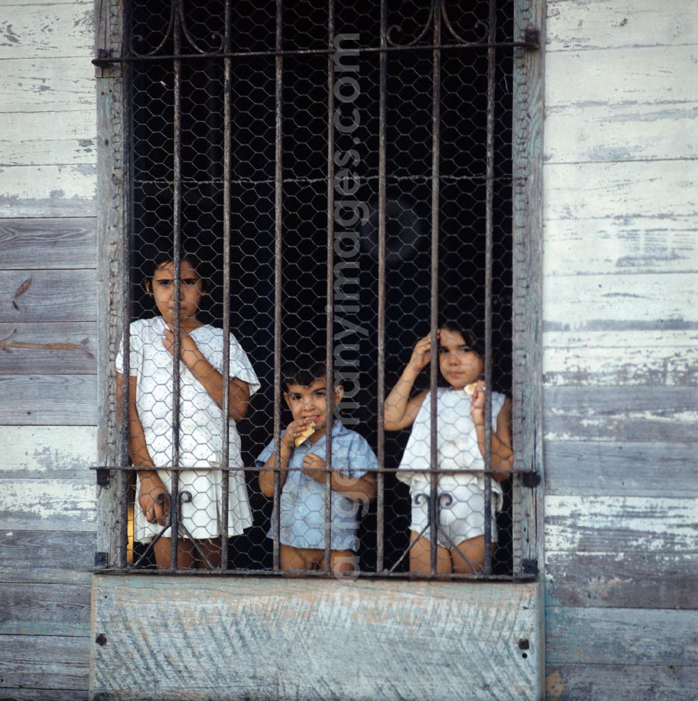 GDR image archive: Nuevitas - Drei Kinder blicken neugierig durch ein vergittertes Fenster in einem Haus in der kubanischen Hafenstadt Nuevitas. Children at the window in the port city Nuevitas.