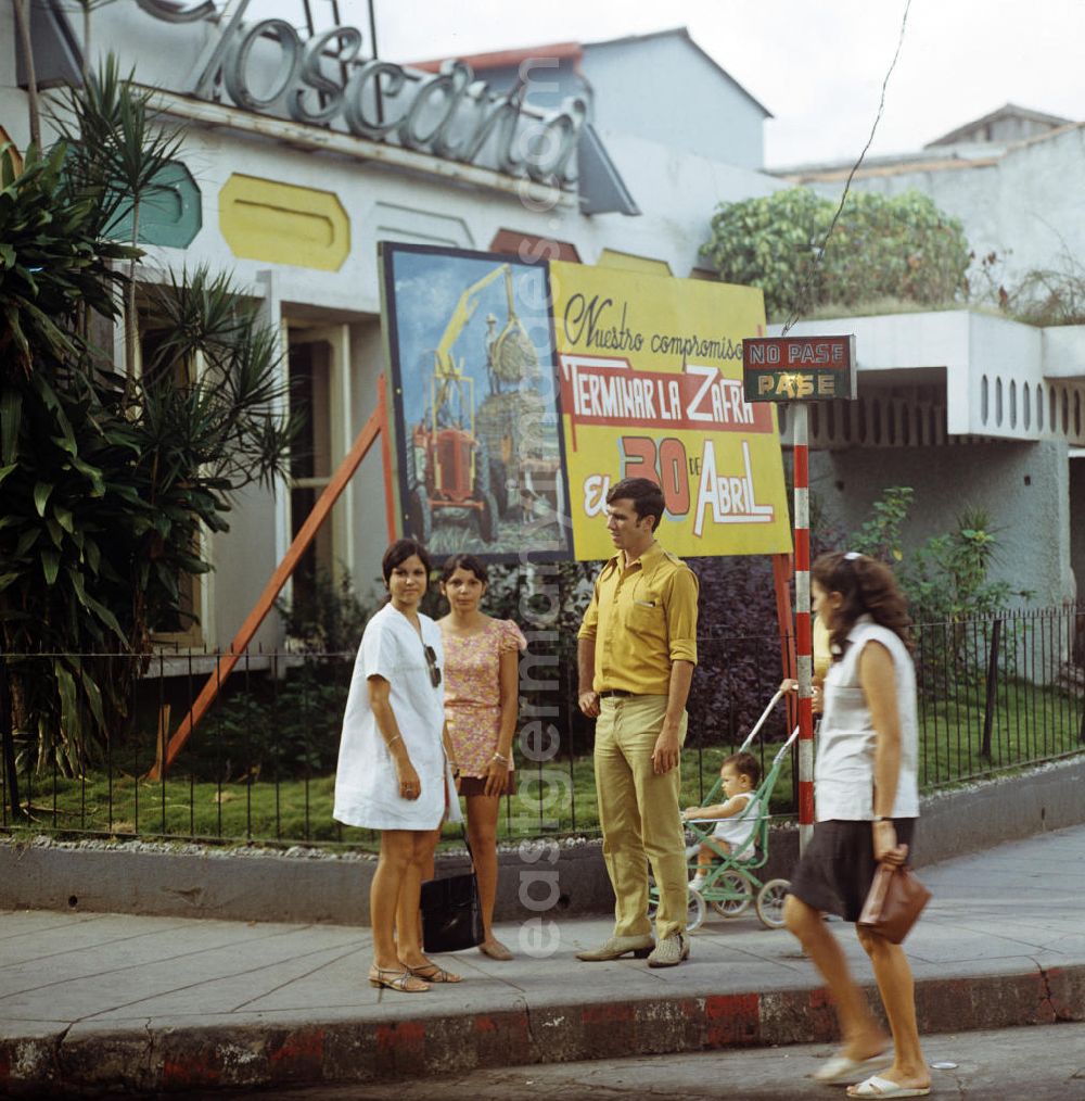 GDR image archive: Santa Clara - Straßenszene in Santa Clara in Kuba - eine Familie steht vor einem Plakat für die sogenannte Zafra, die kubanische Zuckerrohrernte. Street scene in Santa Clara - Cuba.