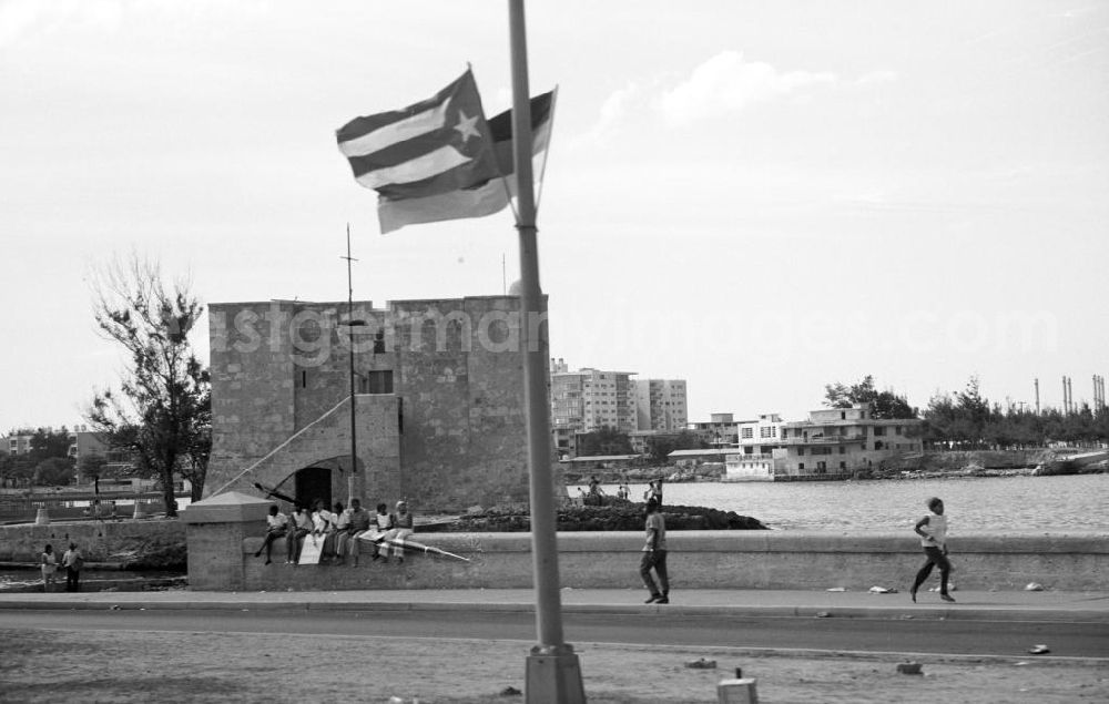 GDR photo archive: Havanna - Eine Gruppe Jugendlicher sitzt mit Plakaten zur Ankunft des Staats- und Parteivorsitzenden der DDR, Erich Honecker, auf der Ufermauer an der Promenade Malecón in Havanna. Honecker stattete vom 2