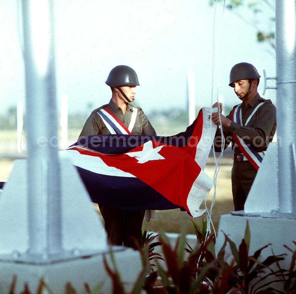 GDR picture archive: Santiago de Cuba - Zum Empfang des Staats- und Parteivorsitzenden der DDR, Erich Honecker, auf dem Flughafen Santiago de Cuba wird von zwei Soldaten die kubanische Flagge gehißt. Honecker stattete vom 2