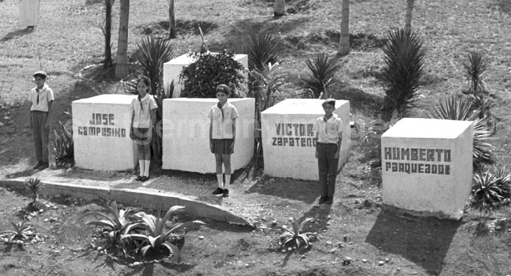 GDR picture archive: Siboney - Zur Besichtigung der Granjita Siboney - einer Kultstätte der kubanischen Revolution - durch den Staats- und Parteivorsitzenden der DDR, Erich Honecker, stehen kubanische Pioniere an kleinen Denkmälern, die entlang der Straße zwischen Santiago de Cuba und Siboney zur Erinnerung an die beteiligten Revolutionäre aufgestellt sind. Die ehemalige Hühnerfarm hatte 1953 den Rebellen um Fidel Castro während der Planung des Sturms auf die Moncada-Kaserne in Santiago als Versteck gedient. Hier waren gefälschte Soldatenuniformen genäht und in einem trockenen Brunnen Waffen versteckt worden. - Honecker stattete vom 2