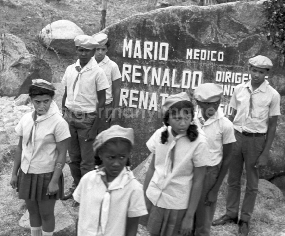 Siboney: Zur Besichtigung der Granjita Siboney - einer Kultstätte der kubanischen Revolution - durch den Staats- und Parteivorsitzenden der DDR, Erich Honecker, stehen kubanische Pioniere an kleinen Denkmälern, die entlang der Straße zwischen Santiago de Cuba und Siboney zur Erinnerung an die beteiligten Revolutionäre aufgestellt sind. Die ehemalige Hühnerfarm hatte 1953 den Rebellen um Fidel Castro während der Planung des Sturms auf die Moncada-Kaserne in Santiago als Versteck gedient. Hier waren gefälschte Soldatenuniformen genäht und in einem trockenen Brunnen Waffen versteckt worden. - Honecker stattete vom 2