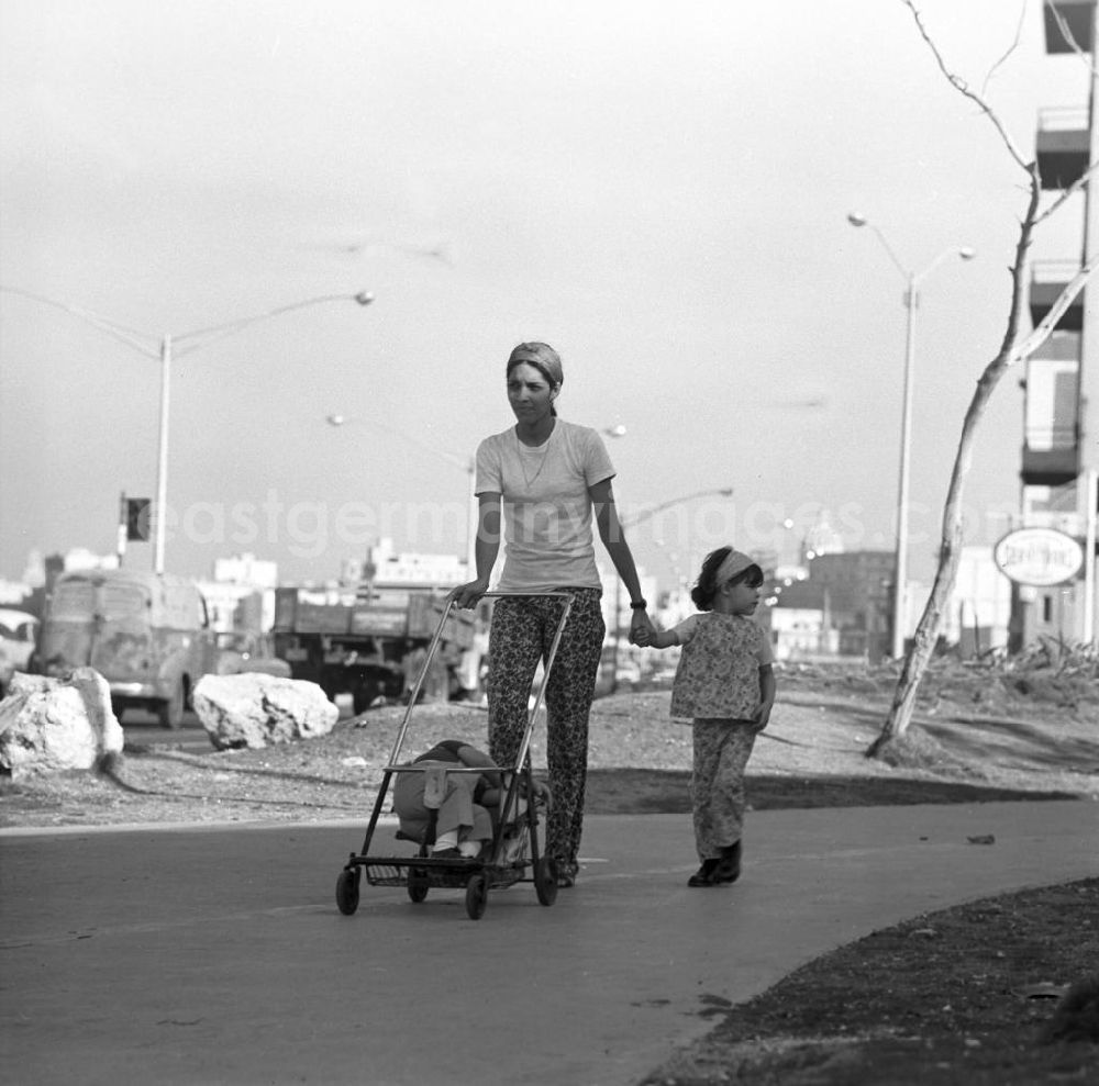 Havanna: Eine Frau mit ihren zwei Kindern auf einem Fußweg in Havanna - das kleinere Kind ist im spärlich ausgestatteten Kinderwagen eingeschlafen.