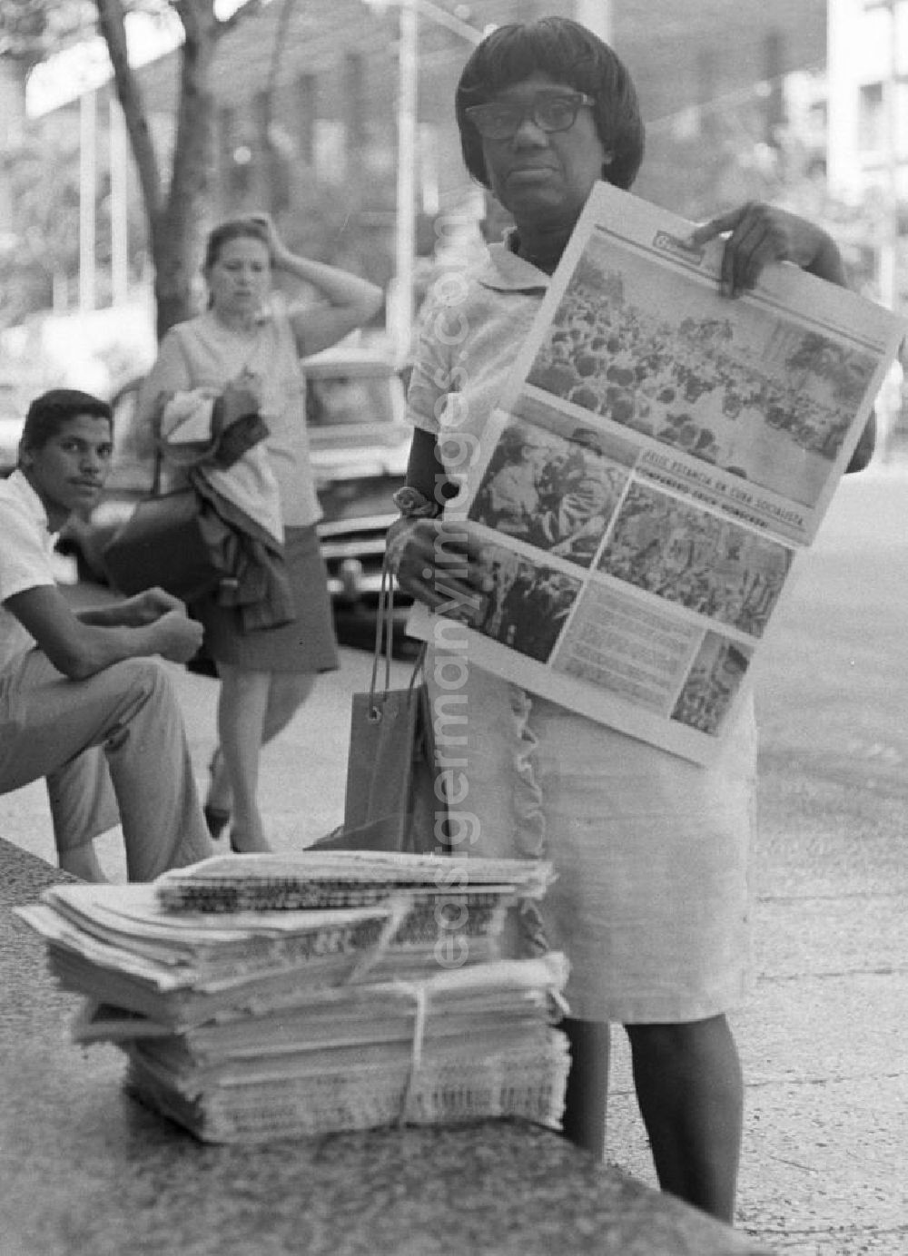 GDR picture archive: Havanna - Eine Zeitungsverkäuferin hält auf einer Straße in Havanna die aktuelle Ausgabe der Granma, der offiziellen Zeitung der Kommunistischen Partei Kubas (PCC), in die Kamera. An diesem Tag ist die Zeitung voll mit Berichterstattungen und Fotos von der Ankunft des Staats- und Parteivorsitzenden der DDR, Erich Honecker, der vom 2