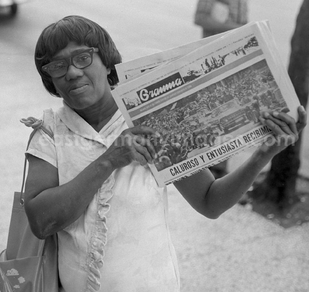 GDR image archive: Havanna - Eine Zeitungsverkäuferin hält auf einer Straße in Havanna die aktuelle Ausgabe der Granma, der offiziellen Zeitung der Kommunistischen Partei Kubas (PCC), in die Kamera. An diesem Tag ist die Zeitung voll mit Berichterstattungen und Fotos von der Ankunft des Staats- und Parteivorsitzenden der DDR, Erich Honecker, der vom 2