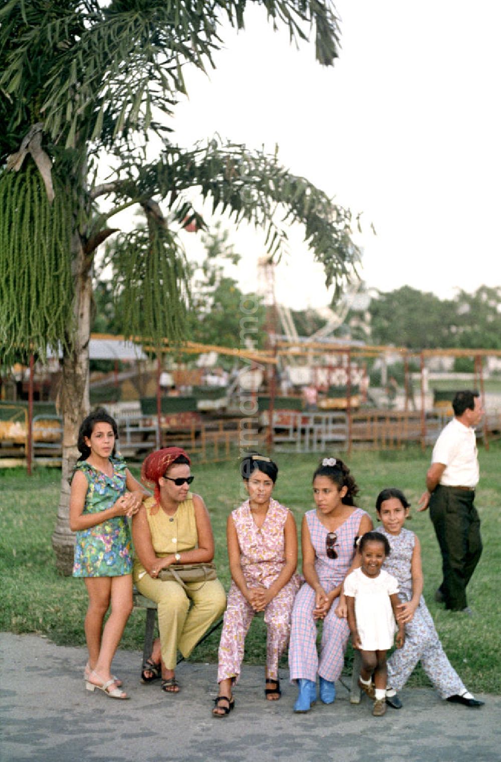 Havanna: Frauen und Kinder sitzen auf einer Bank vor einem kleinen Rummel in Havanna.