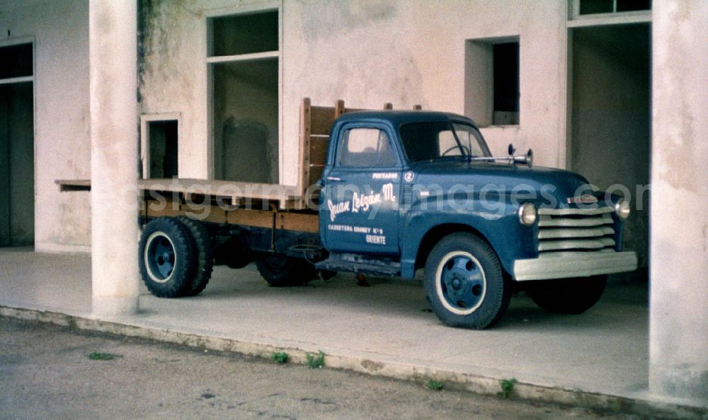 GDR picture archive: Santiago de Cuba - Ein Pritschenwagen steht im Säulengang eines Hauses in Santiago de Cuba.