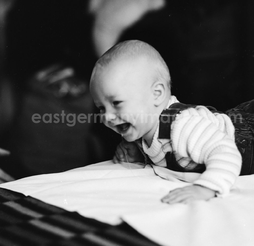 GDR image archive: Berlin - Laughing toddler with overalls on a playmat in Berlin, the former capital of the GDR, the German Democratic Republic