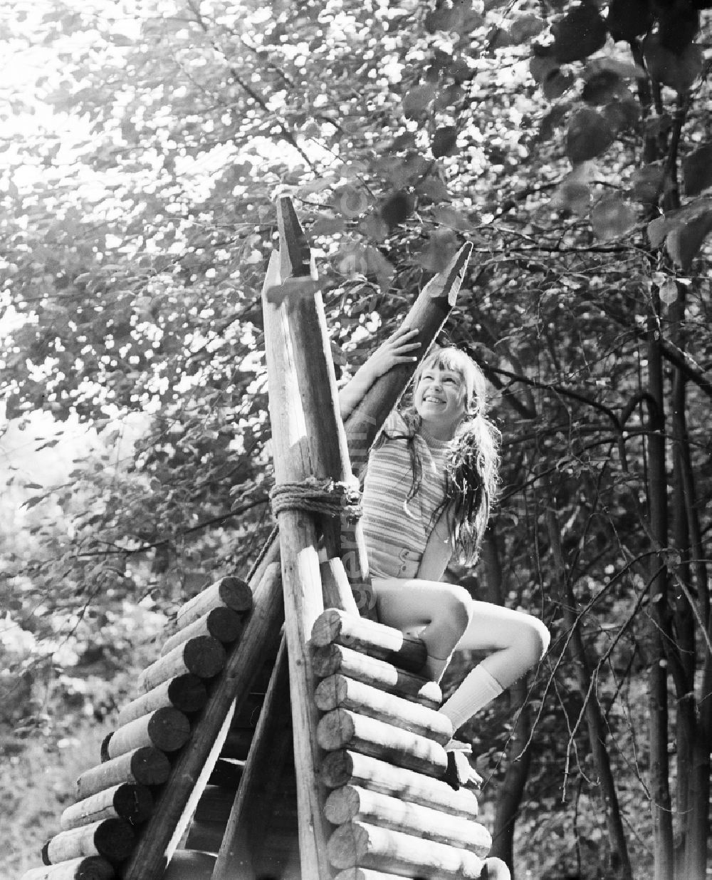 Berlin: Laughing girl on a wooden tepee on a playground in Berlin, the former capital of the GDR, German democratic republic