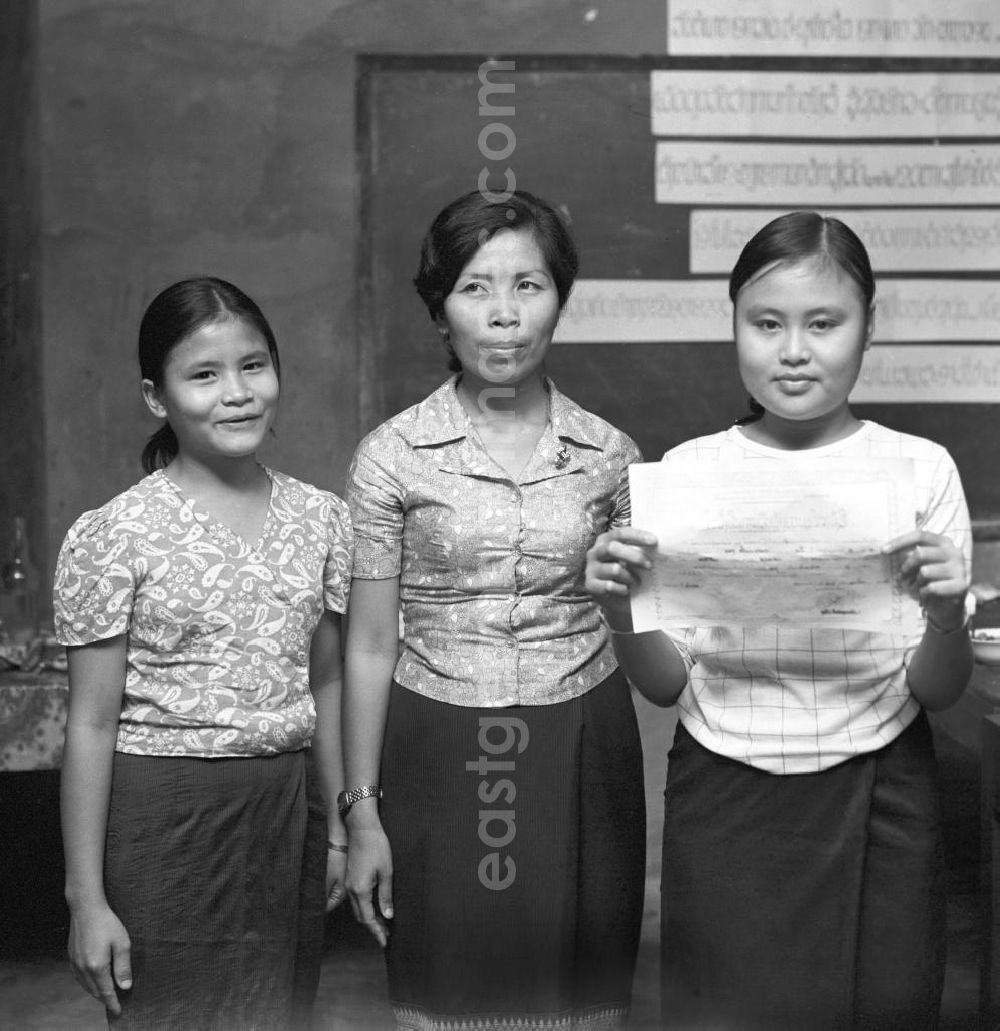 GDR picture archive: Vientiane - Frauen erhalten ihr Diplom für das erfolgreiche Lernen von Lesen und Schreiben in der Demokratischen Volksrepublik Laos. Nach der Gründung der Volksrepublik Laos im Dezember 1975 wurde das Schulsystem von der neuen kommunistischen Regierung in Laos wieder aufgebaut, um dem in der Bevölkerung weit verbreiteten Analphabetismus entgegenzuwirken.
