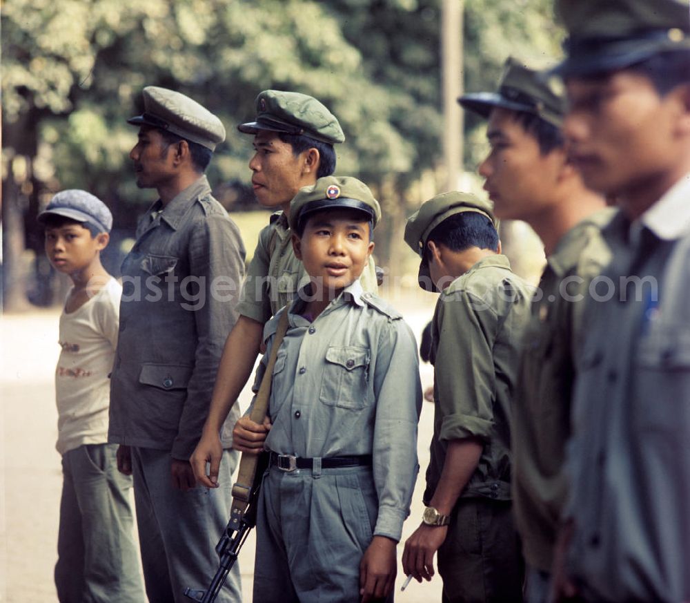 GDR picture archive: Nam Ngum - Soldaten der laotischen Armee, darunter auch Kinder, in der Demokratischen Volksrepublik Laos. Erst ein Jahr zuvor, am 2. Dezember 1975, war durch die kommunistisch geprägten Kräfte die Volksrepublik Laos ausgerufen worden. Die politische und wirtschaftliche Situation blieb aber auch in den Folgejahren unsicher und instabil. Immer wieder kam es zu Rebellionen aus dem Hinterland, die mit Hilfe der Armee und ausländischer, v.a. vietnamesischer, Unterstützung gewaltsam niedergeschlagen wurden.