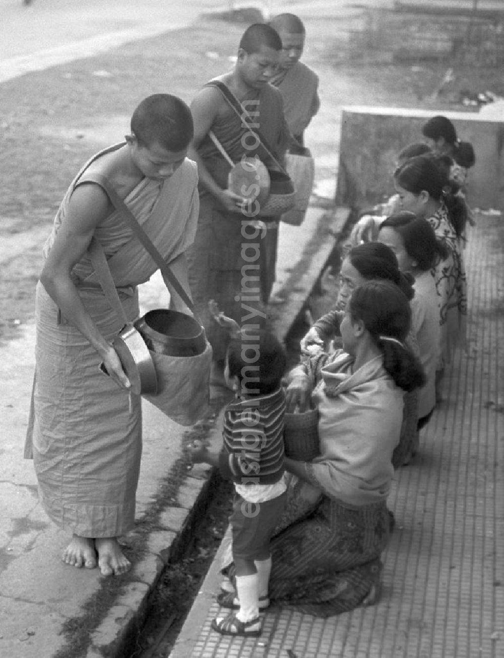 GDR picture archive: Vientiane - Früh am Morgen ziehen Bettelmönche durch Vientiane, der Hauptstadt der Demokratischen Volksrepublik Laos, um sich Essen für den Tag zu erbetteln.