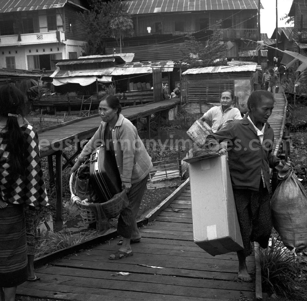 GDR picture archive: Vientiane - Nach einem Brand in einer Wohnhütte bringen die Bewohner ihr Hab und Gut in Sicherheit in Vientiane in der Demokratischen Volksrepublik Laos.