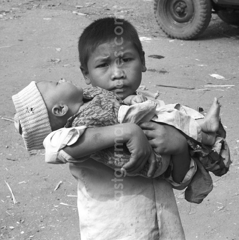 GDR picture archive: Vientiane - Ein Junge hält seinen kleinen Bruder auf dem Arm auf einem Markt östlich von Vientiane in der Demokratischen Volksrepublik Laos.