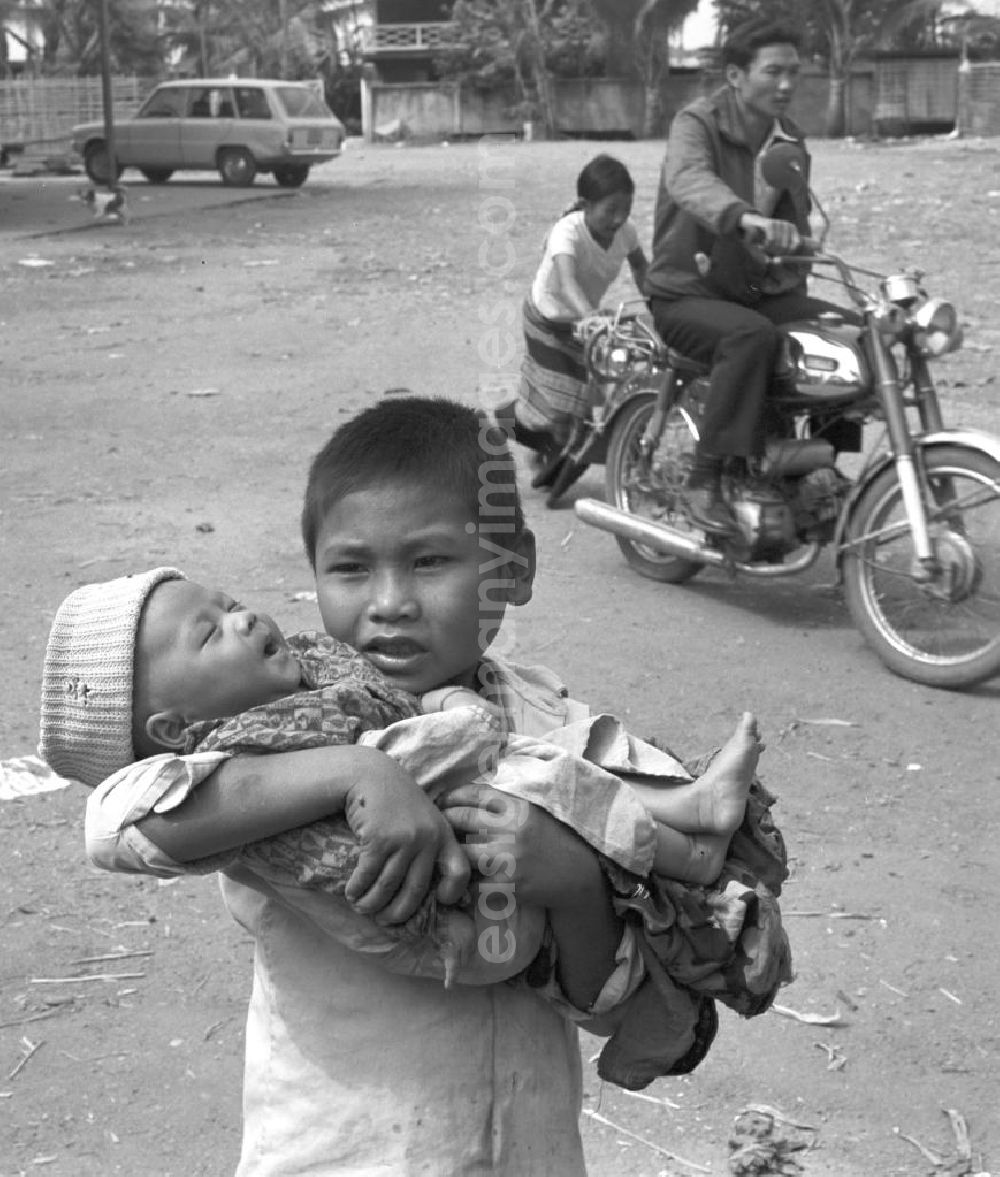 GDR image archive: Vientiane - Ein Junge hält seinen kleinen Bruder auf dem Arm auf einem Markt östlich von Vientiane in der Demokratischen Volksrepublik Laos.