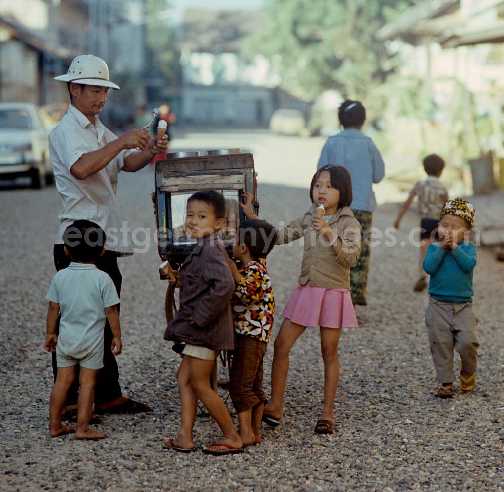 GDR picture archive: Vientiane - Kinder kaufen sich an einem kleinen Eiswagen auf einer Straße in Vientiane in der Demokratischen Volksrepublik Laos ein Eis.