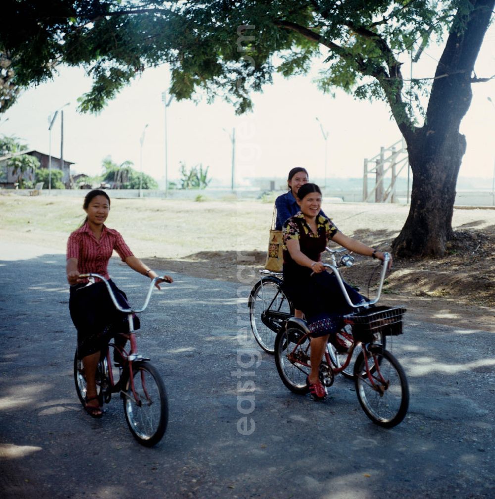 GDR photo archive: Vientiane - Junge Mädchen auf Fahrrädern auf einer Straße in Vientiane in der Demokratischen Volksrepublik Laos.