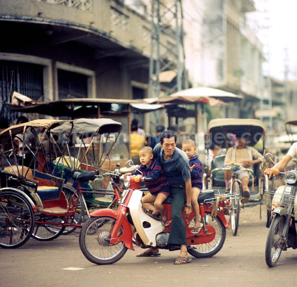 GDR picture archive: Vientiane - Ein Mann mit seinen Kindern auf einem Motorrad in Vientiane in der Demokratischen Volksrepublik Laos.