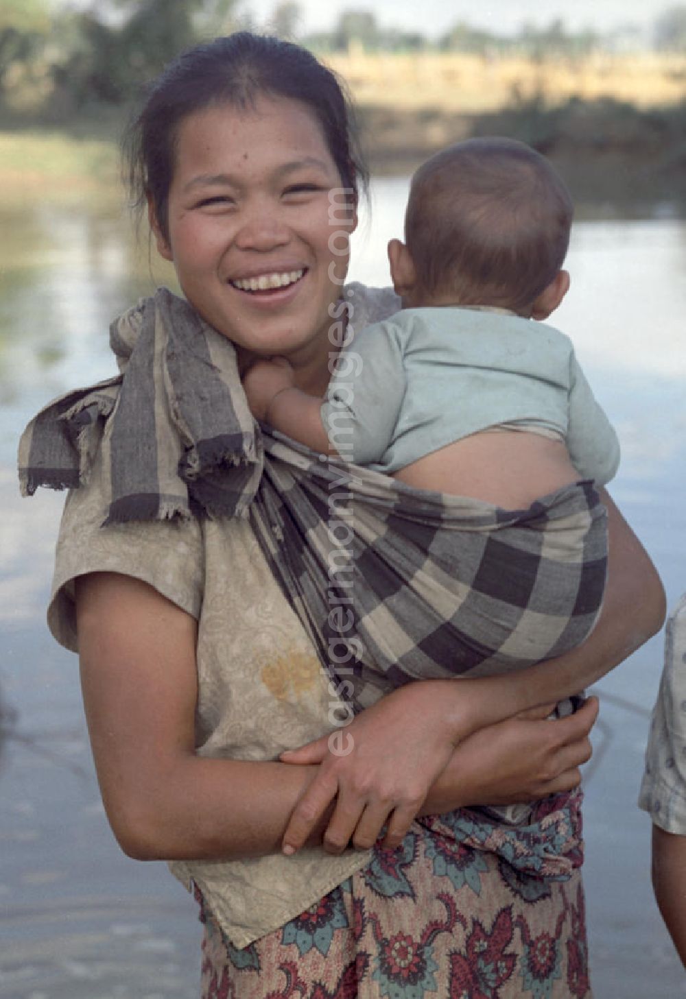 Nam Ngum: Eine Frau hält ihr Baby auf dem Arm am Fluß Nam Ngum in der Demokratischen Volksrepublik Laos.