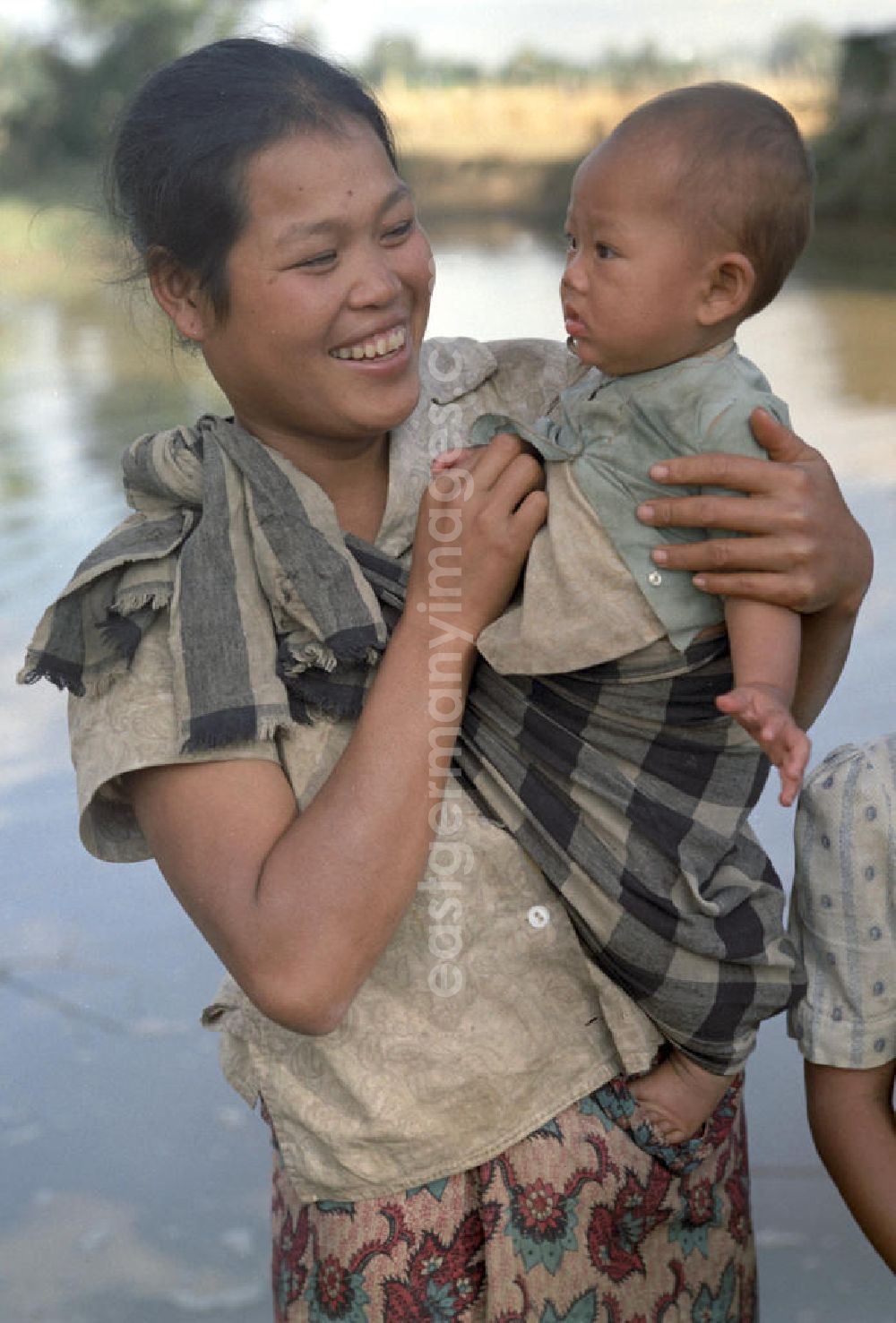GDR photo archive: Nam Ngum - Eine Frau hält ihr Baby auf dem Arm am Fluß Nam Ngum in der Demokratischen Volksrepublik Laos.