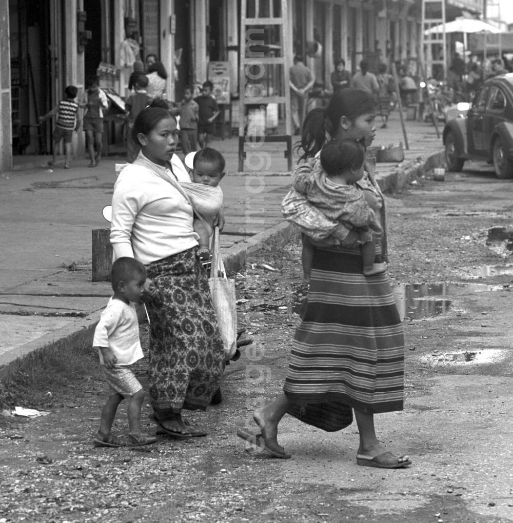 GDR photo archive: Vientiane - Frauen mit Kindern überqueren eine Straße in Vientiane in der Demokratischen Volksrepublik Laos.