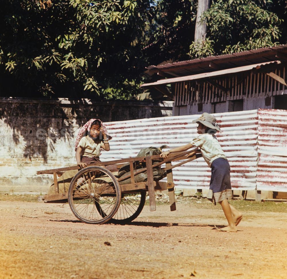 Vientiane: Ein Mädchen schiebt einen beladenen Karren auf einer Straße in Vientiane in der Demokratischen Volksrepublik Laos.