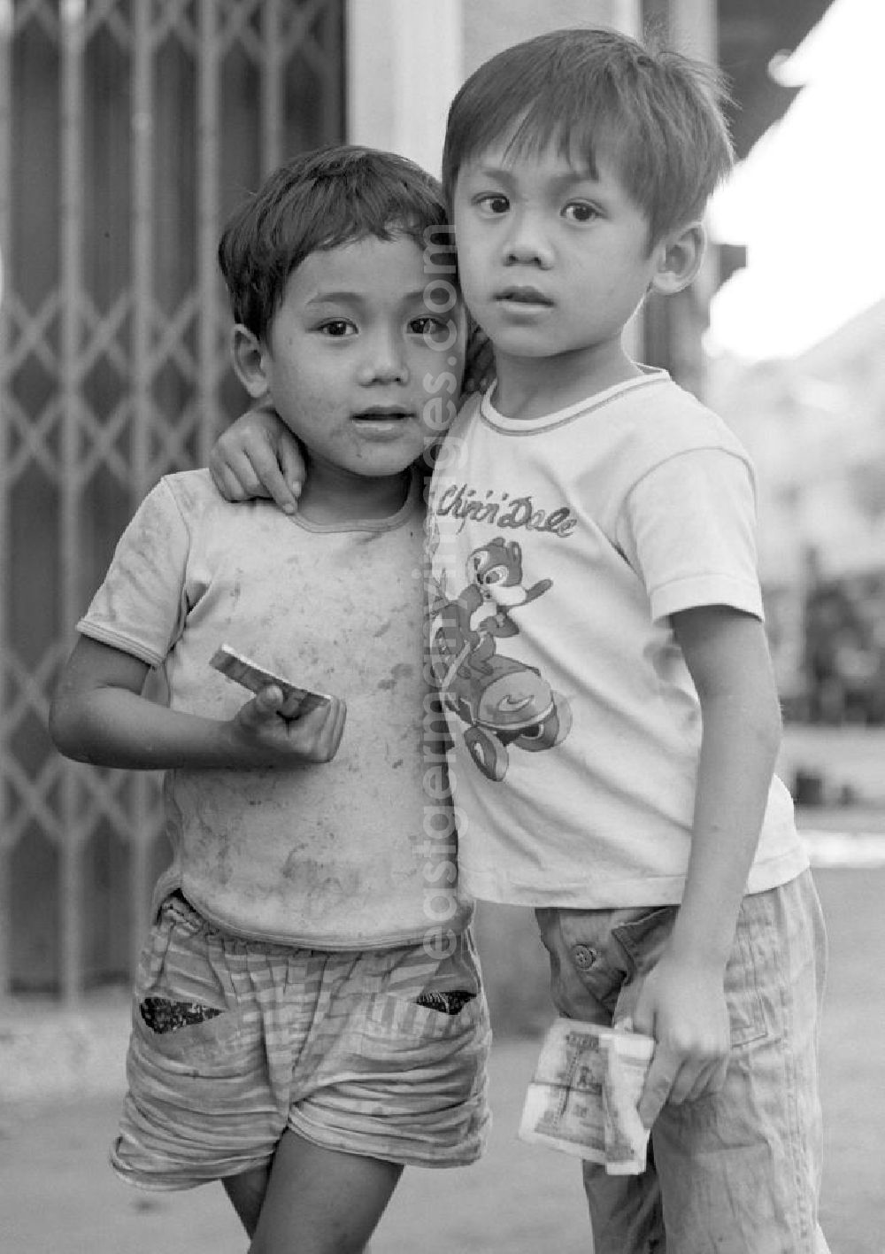 GDR photo archive: Vientiane - Zwei Kinder auf einer Straße in Vientiane, der Hauptstadt der Demokratischen Volksrepublik Laos. Ein Kind trägt ein T-Shirt mit den Chip 'n' Dale, zwei Trickfilmfiguren von Walt Disney.