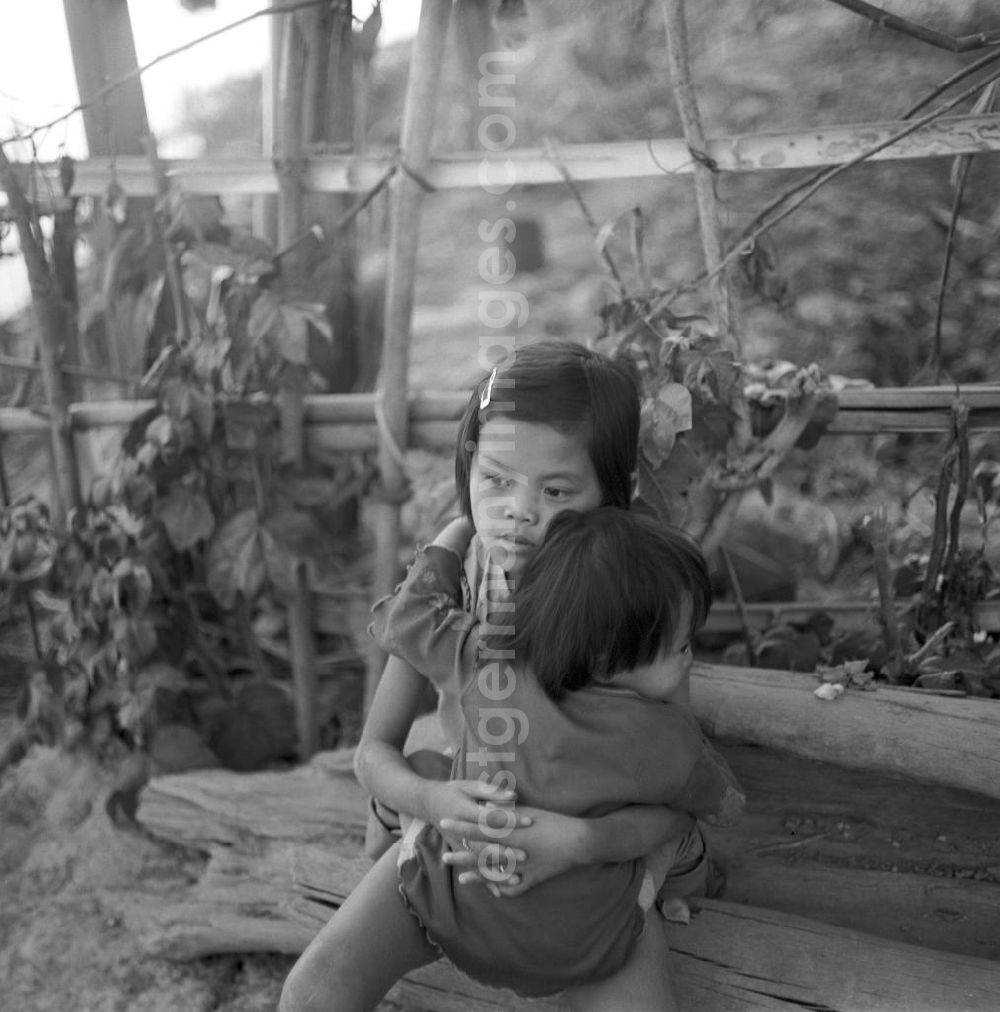 GDR picture archive: Vientiane - Zwei Kinder sitzen am Ufer des Mekong in der Demokratischen Volksrepublik Laos.
