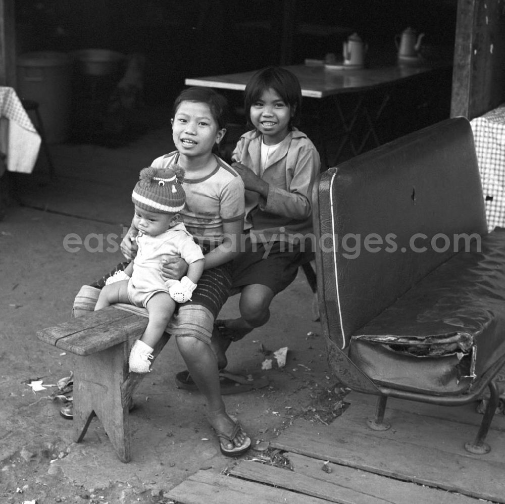 Vientiane: Mädchen sitzen auf einer Bank vor ihrem Haus und flechten sich die Haare in Vientiane in der Demokratischen Volksrepublik Laos.