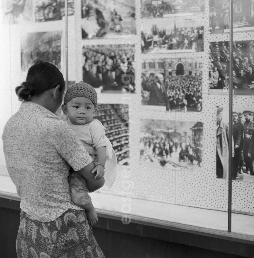Vientiane: Ein Jahr nach der Gründung der Volksrepublik Laos im Dezember 1975 betrachtet eine Frau mit ihrem Baby auf dem Arm in einem Schaukasten ausgestellte Lenin-Bilder von der russischen Oktoberrevolution in Vientiane in der Demokratischen Volksrepublik Laos.