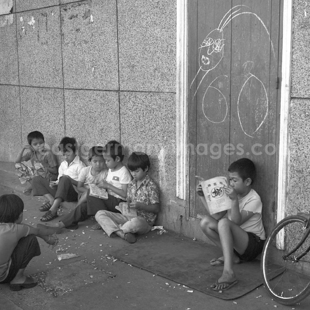 GDR picture archive: Vientiane - Kinder lesen am Rande des Marktes in Vientiane in der Demokratischen Volksrepublik Laos.